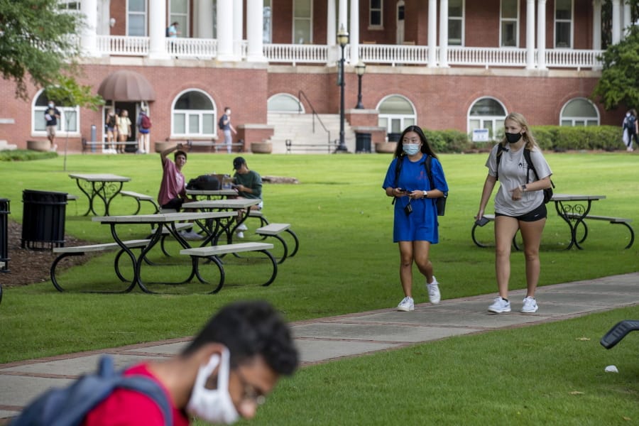 FILE - In this Aug. 21, 2020, file photo, Georgia College and State University freshmen Ashlynn Anglin, right, and Meghan Murphy, second from right, wear face masks as they talk while walking through the campus in Milledgeville, Ga. As more and more schools and businesses around the country get the OK to reopen, some college towns are moving in the opposite direction because of too much partying and too many COVID-19 infections among students.