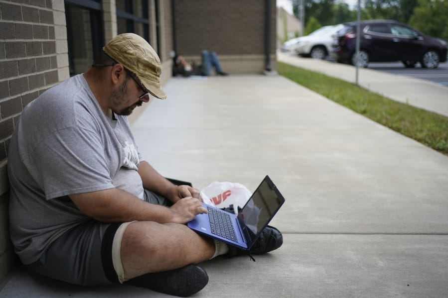 Barlow Mitchell sits outside the Lee County Public Library while using the public WIFI, in Beattyville, Ky., Wednesday, July 29, 2020. As in other places, parents and officials are concerned about the virus, but dramatically limited internet access in many rural places also means kids could fall seriously behind if the pandemic keeps them home again.