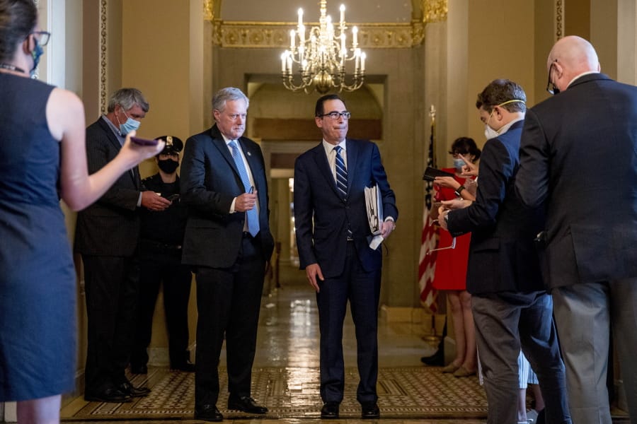 Treasury Secretary Steven Mnuchin, right, accompanied by White House chief of staff Mark Meadows, left, take a question from a reporter following a meeting with Senate Majority Leader Mitch McConnell of Ky. as negotiations continue on a coronavirus relief package on Capitol Hill in Washington, Tuesday, Aug. 4, 2020.