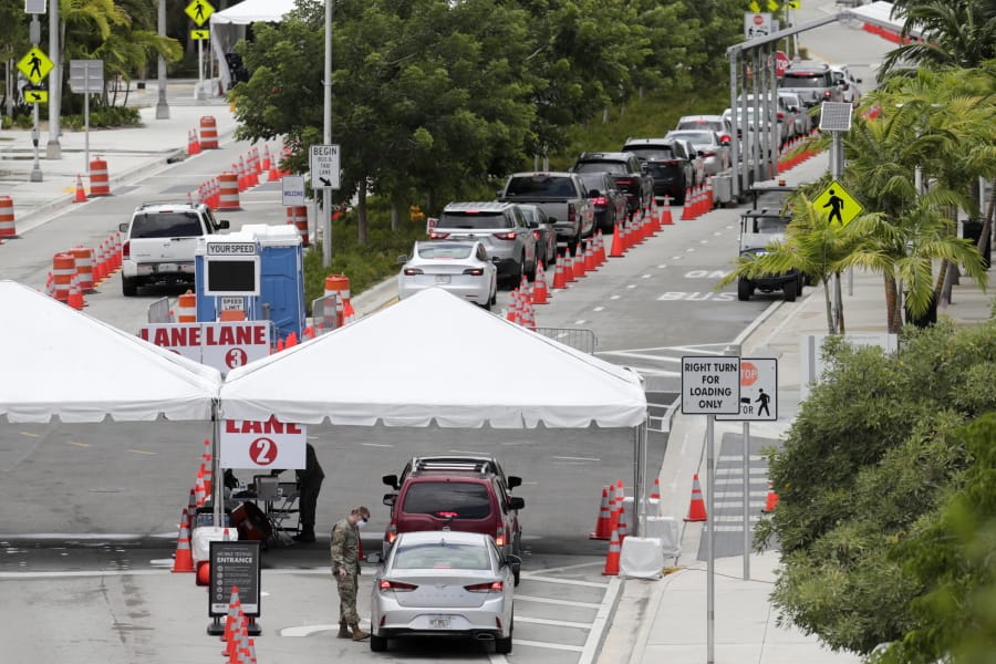 FILE - In this Sunday, July 12, 2020, vehicles wait in line at a COVID-19 testing site at the Miami Beach Convention Center during the coronavirus pandemic in Miami Beach, Fla. As coronavirus cases surge in hard-hit Florida, so do the turnaround times for test results.