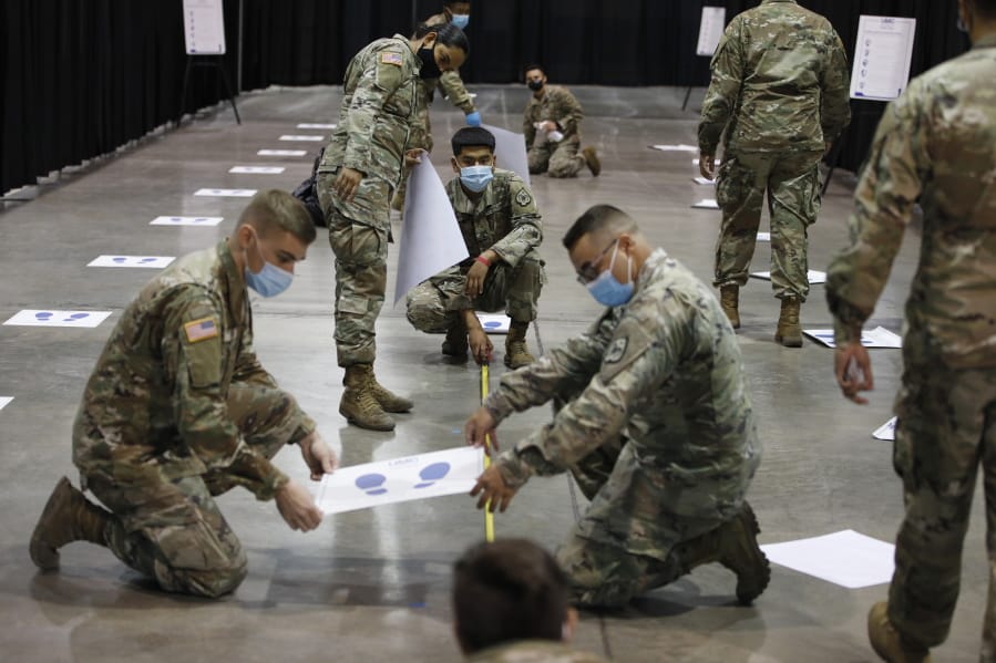 Members of the Nevada National Guard install social distancing stickers while setting up a new temporary coronavirus testing site Monday, Aug. 3, 2020, in Las Vegas.