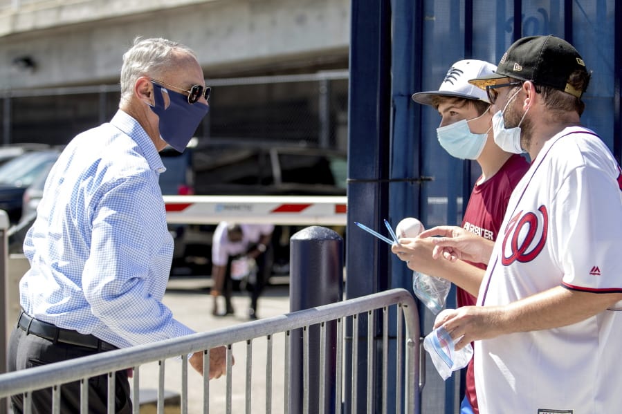 MLB Commissioner Rob Manfred, left, speaks with fans as he arrives at Nationals Park for the New York Yankees and the Washington Nationals opening day baseball game, Thursday, July 23, 2020, in Washington.