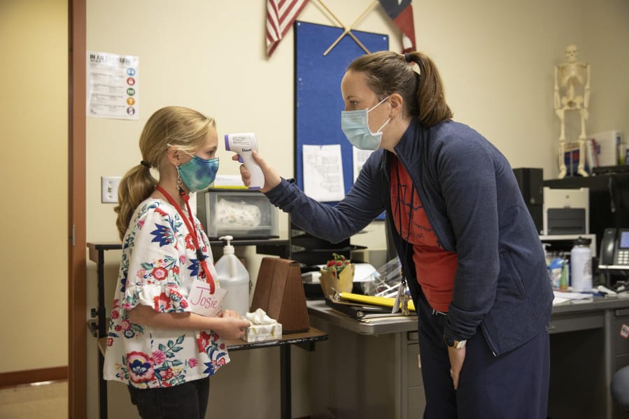 School nurse Annie Wood takes the temperature of fourth-grader Josie Valentine, 9, at Jacob&amp;rsquo;s Well Elementary School in Wimberley on Thursday. School nurses will be on the front lines in helping detect and prevent the spread of the coronavirus in schools.