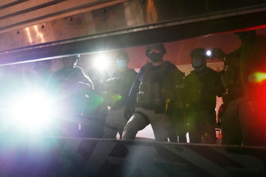 Federal officers shine flashlights from inside a closing garage door at the rear entrance to the Mark O. Hatfield U.S. Courthouse on July 31, 2020 in Portland, Oregon.