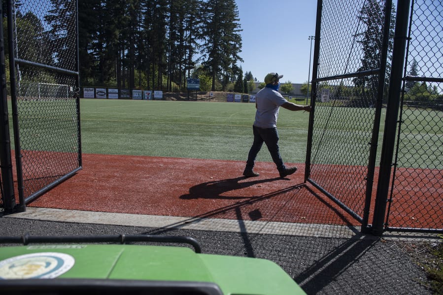 Roy Flores, a grounds maintenance specialist, opens the gate to a baseball and soccer field at Luke Jensen Sports Park.