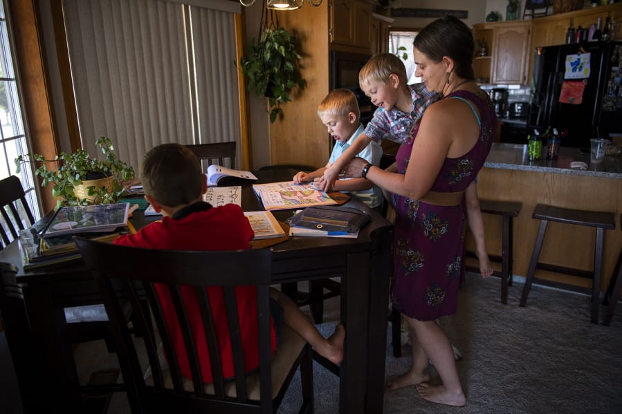 Oliver Emerick, 6, from left, does math problems with his cousin Mavric Martin, 5, as Mavric&#039;s brother Hendric, 3, and their mother, Chelsey Martin, help them at their home in Battle Ground on Sept. 4. Chelsey Martin and her sister-in-law Kati Emerick have joined forces to teach their sons kindergarten amid school closures and health concerns due to the coronavirus pandemic.