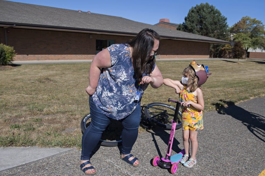 Kindergarten teacher Miranda Roderick, left, greets kindergartner Avery Anderson, 5, as she cruises by River HomeLink with her family to pick up materials for the upcoming school year. Enrollment in Alternative Learning Experiences, such as River HomeLink, is up while school districts operate remotely.