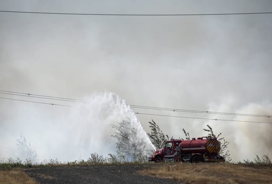 A water tender is put to use fighting a brush fire off Fruit Valley Road and Northwest Lower River Road late Tuesday afternoon.