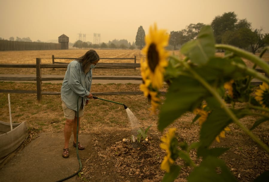 Heisson resident and volunteer Elizabeth Stoltz waters the Fort Vancouver Garden in Vancouver on Friday. Stoltz said things were dried out because of the wind and smoke. &quot;The wind sucks the life out of everything,&quot; she said. Stoltz is still not under evacuation from the Big Hollow Fire, but her family made a plan in case it gets to that point.