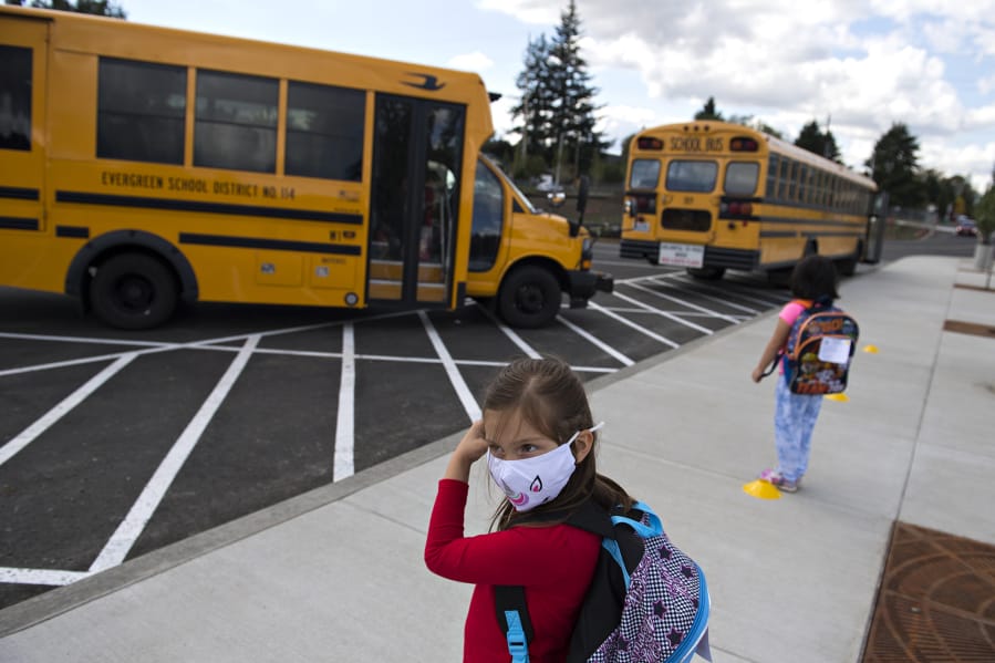 Kindergartner Evalynn Pratt, 5, secures her face mask while waiting for her classmates to arrive on the bus at Sifton Elementary School in September.