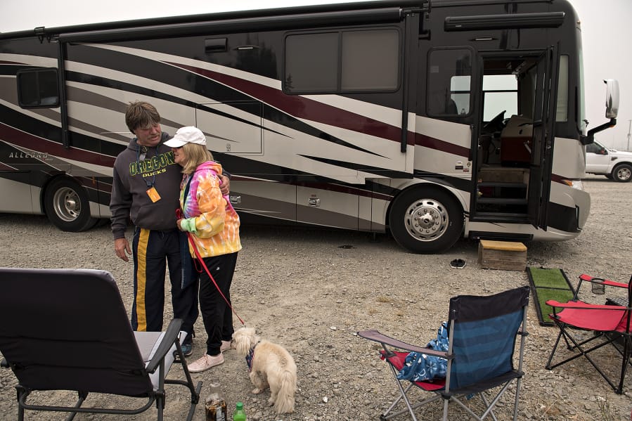 Doug Lewis of Canby, Ore., embraces his partner, Judi Christiansen, while joined by her dog, Josie, 17, in the parking lot at ilani on Saturday. The pair were also joined by Lewis&#039; sister, Bev, who is the owner of the motor home they are sleeping in. The three are staying in the casino parking lot as they escape the wildfires burning near their homes in Oregon. &quot;We don&#039;t know what we&#039;re going to come back to,&quot; Lewis said.
