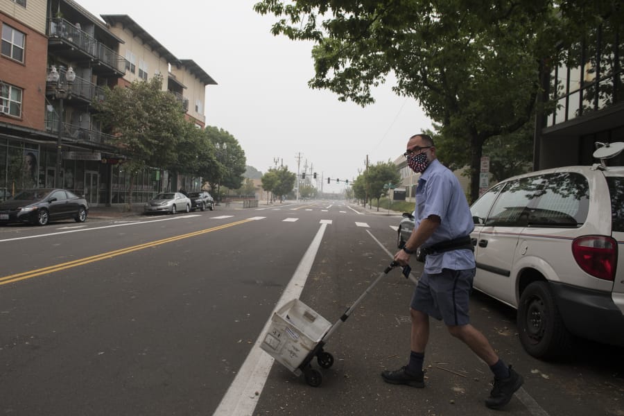 Thick wildfire smoke is seen overhead as letter carrier Jon Weinberg works in downtown Vancouver. Smoke levels continue to hover in the hazardous air quality range.