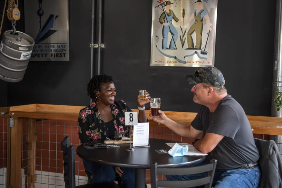 Bella Roushall, left, and her husband, Scott, enjoy beers together Saturday at Trusty Brewing in Vancouver.