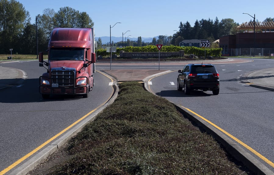 Drivers of a truck and an SUV navigate a roundabout east of Interstate 5 along South Pioneer Street in Ridgefield on Tuesday morning. Below, a motorist passes construction in Ridgefield near the intersection of South Fifth Street and Union Ridge Parkway, which is not part of the grant project but will connect to it, on Tuesday morning.