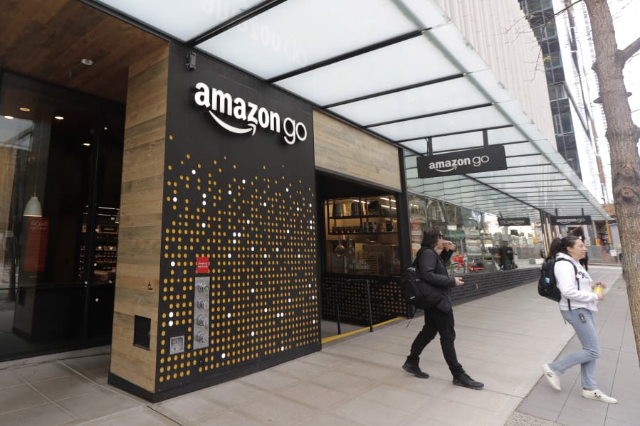 FILE - In this March 4, 2020 file photo, people walk out of an Amazon Go store, in Seattle. Amazon is rolling out a new device for contactless transactions that will scan an individual&#039;s palm. The Amazon One, which will initially launch in two Amazon Go stores in Seattle, is being viewed as a way for people to use their palm to make everyday activities like paying at a store easier. (AP Photo/Ted S.