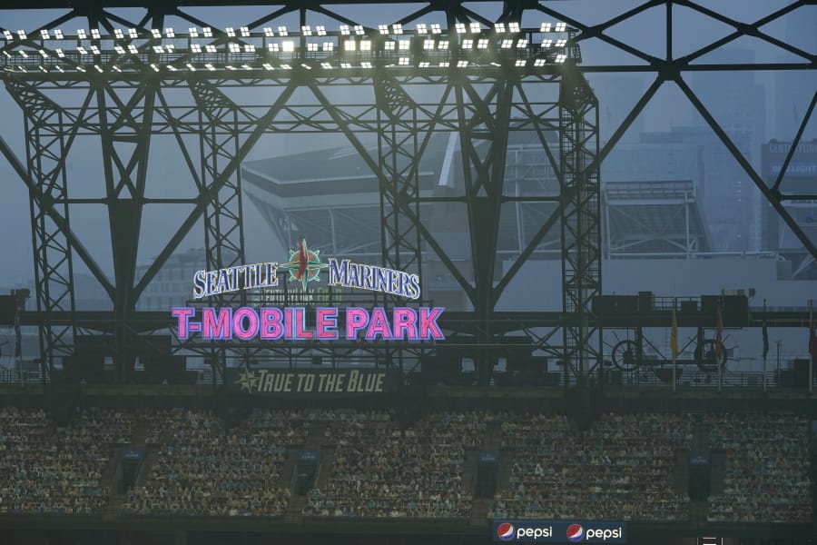 Smoke from wildfires fills the air at T-Mobile Park as photos of fans are displayed in the left field bleachers and CenturyLink Field is visible behind the ballpark sign during the second baseball game of a doubleheader between the Seattle Mariners and the Oakland Athletics, Monday, Sept. 14, 2020, in Seattle. (AP Photo/Ted S.