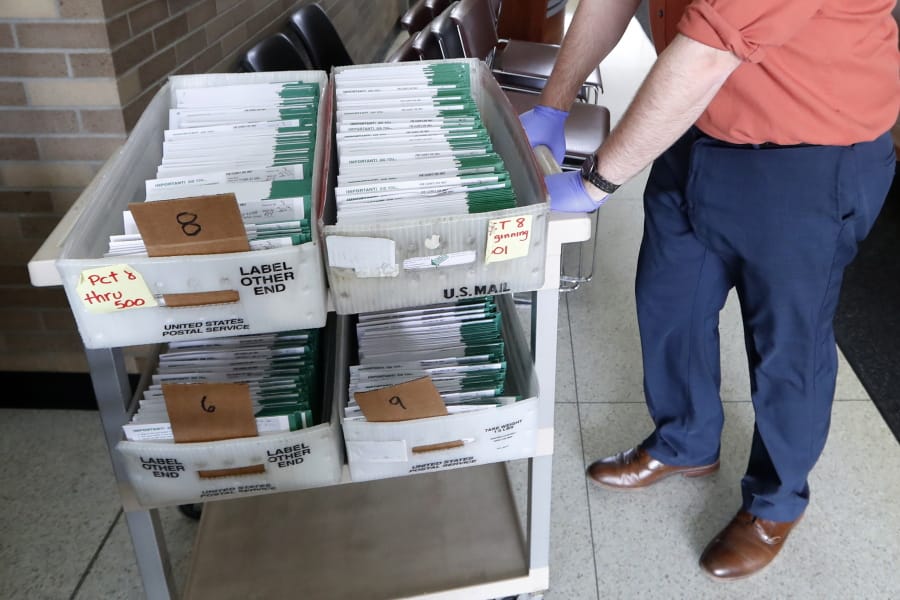 FILE - In this May 5, 2020, file photo, absentee ballots to be counted are moved at City Hall in Garden City, Mich. Data obtained by The Associated Press shows Postal Service districts across the nation are missing the agency&#039;s own standards for on-time delivery as millions of Americans prepare to vote by mail.