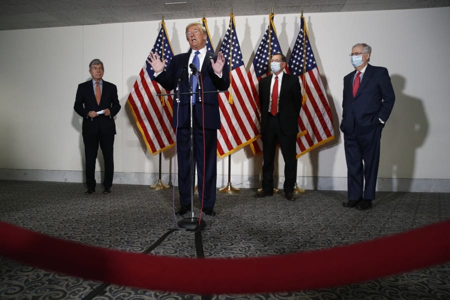 FILE - In this May 19, 2020, file photo President Donald Trump speaks with reporters after meeting with Senate Republicans at their weekly luncheon on Capitol Hill in Washington. Standing behind Trump are Sen. Roy Blunt, R-Mo., from left, Sen. John Barrasso, R-Wyo., and Senate Majority Leader Mitch McConnell of Ky. The battle for control of Congress this fall is solidifying into a race about Trump.