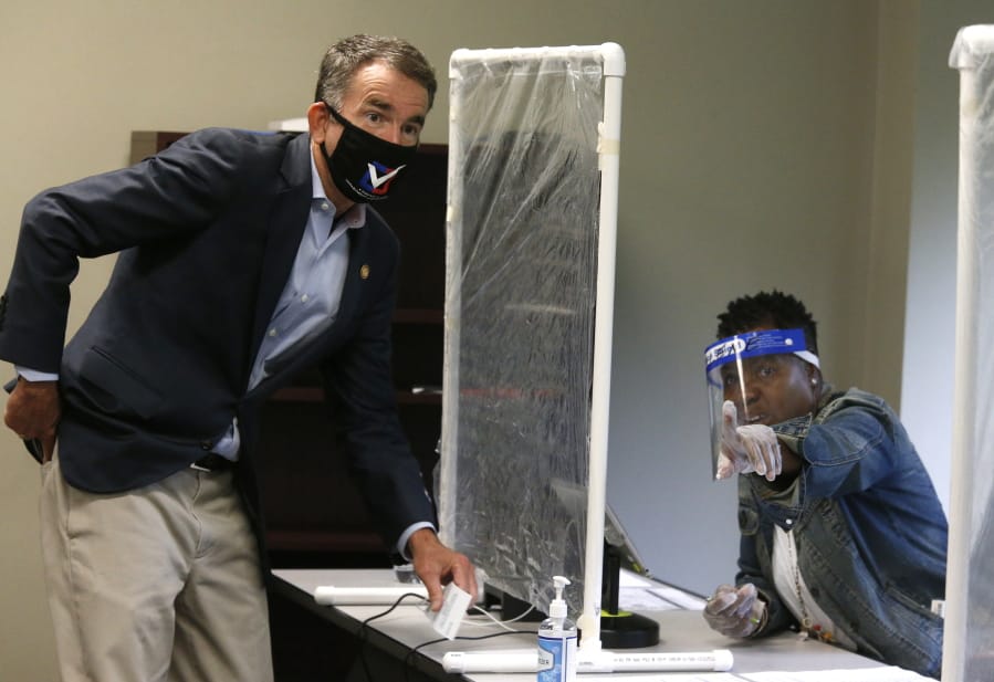 Virginia Gov. Ralph Northam, left, is shown by a poll worker which way to go as he votes early at the Richmond general registrar&#039;s office in Richmond, Va., Friday, Sept. 18, 2020, on the first day of Virginia&#039;s 45-day early voting period.