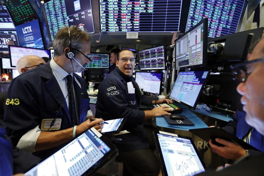FILE - In this Aug. 21, 2019, file photo, specialist Anthony Matesic, center, works with traders at his post on the floor of the New York Stock Exchange. Stocks are opening solidly higher on Wall Street Monday, Sept. 14, 2020, following a burst of big corporate deals.