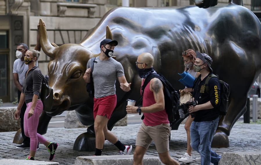 FILE - In this Tuesday, Sept. 8, 2020, file photo, people wearing masks pass the Charging Bull statue in New York&#039;s financial district. Wall Street is steadying itself Wednesday following its first three-day losing streak in nearly three months, as the bloodletting for big technology stocks comes to at least a temporary halt.