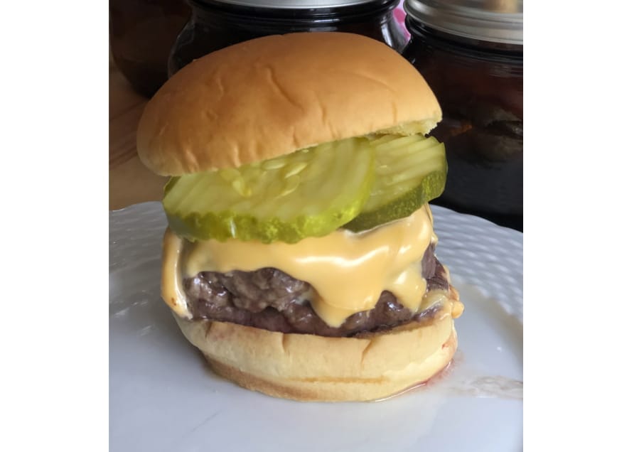 This June 2020 photo shows a cheeseburger topped with pickles in Alexandria, Va. To get the best tasting burger, try making your own  blend with better quality cuts of beef.
