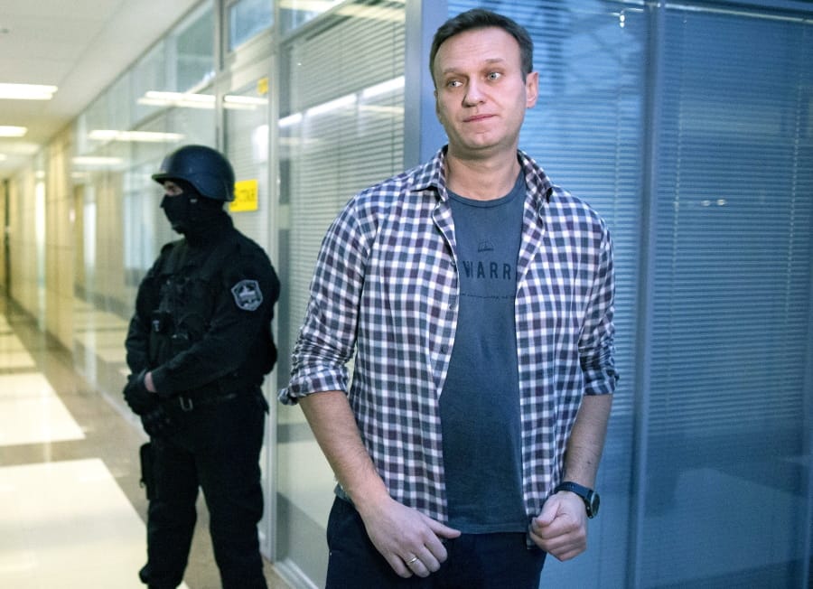 FILE- In this Dec. 26, 2019, file photo, Russian opposition leader Alexei Navalny speaks to the media in front of a security officer standing guard at the Foundation for Fighting Corruption office in Moscow, Russia. The German government says specialist labs in France and Sweden have confirmed Russian opposition leader Alexei Navalny was poisoned with the Soviet-era nerve agent Novichok.