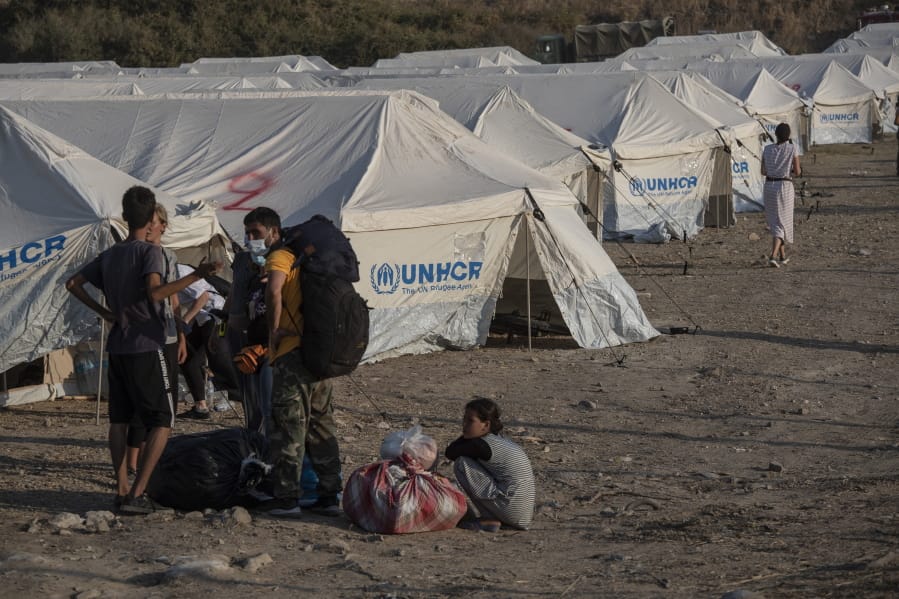 Migrants arrive at a temporary camp near Mytilene town, on the northeastern island of Lesbos, Greece, Saturday, Sept. 12, 2020. Greek authorities have been scrambling to find a way to house more than 12,000 people left in need of emergency shelter on the island after the fires deliberately set on Tuesday and Wednesday night gutted the Moria refugee camp.