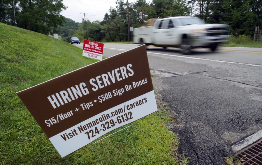 FILE - In this Wednesday, Sept. 2, 2020, file photo help wanted signs for servers and cooks at Nemacolin Woodlands Resort and Spa are displayed along route 40 at the entrance to the resort in Farmington, Pa. U.S. employers advertised more jobs but hired fewer workers in July, sending mixed signals about a job market in the wake of the coronavirus outbreak. The Labor Department said Wednesday, Sept. 9, 2020, that the number of U.S. job postings on the last day of July rose to 6.6 million from 6 million at the end of June. (AP Photo/Gene J.