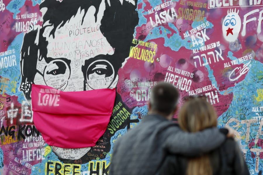 A couple look at the &quot;Lennon Wall&quot; with a face mask attached to the image of John Lennon, in Prague, Czech Republic, on April 6. Like so many other events in the year of coronavirus, an annual tribute to John Lennon held in his adopted city of New York will go online.