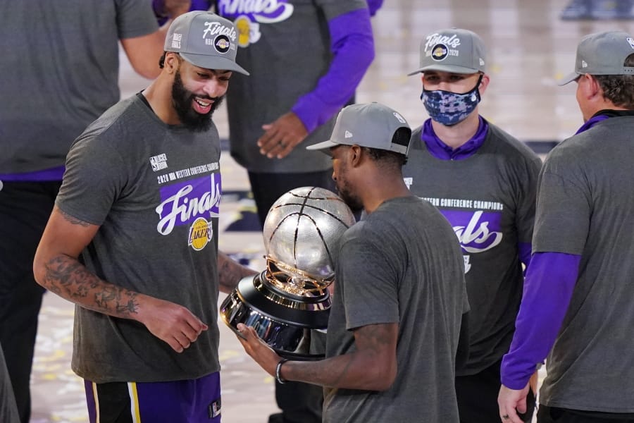 Los Angeles Lakers&#039; Anthony Davis, left, looks at their trophy after beating the Denver Nuggets in an NBA conference final playoff basketball game Saturday, Sept. 26, 2020, in Lake Buena Vista, Fla. The Lakers won 117-107 to win the series 4-1. (AP Photo/Mark J.