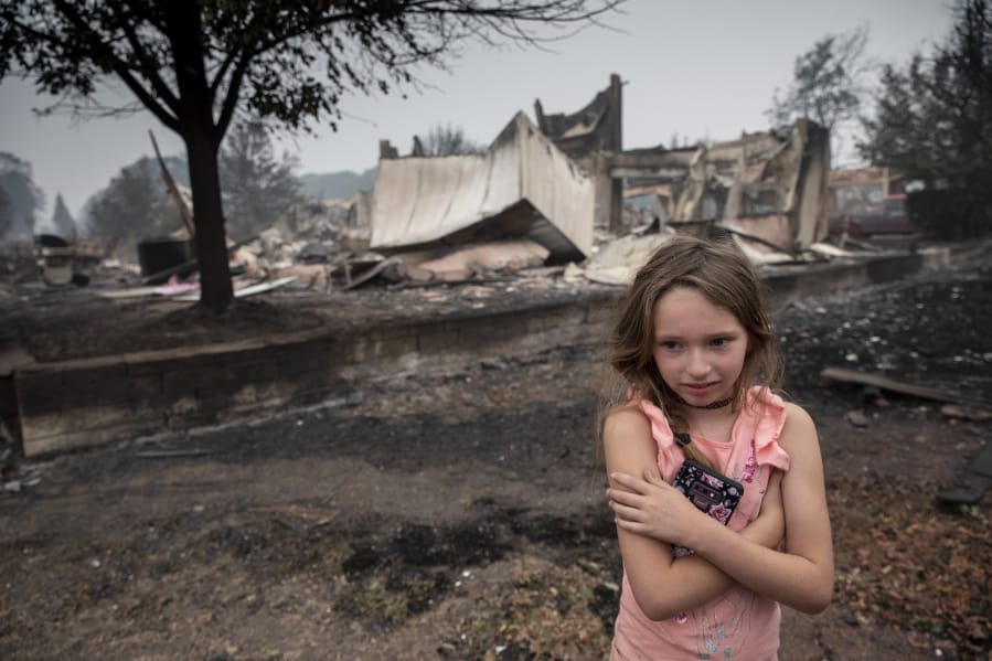 Ellie Owens, 8, from Grants Pass, Ore., looks at fire damage Friday, Sept. 11, 2020, as destructive wildfires devastate the region in Talent, Ore.