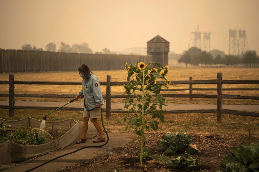 Volunteer Elizabeth Stoltz of Heisson waters the Fort Vancouver Garden in Vancouver, Wash., Friday, Sept. 11, 2020. Stolz said things were extra dried out because of the wind and smoke. &quot;The wind sucks the life out of everything,&quot; she said. Stoltz said she is still not under evacuation from the Big Hollow Fire but her family made a plan in case it gets to that point. Clark County entered hazardous air-quality territory late Thursday as wildfire smoke traveling from other areas enveloped Southwest Washington.