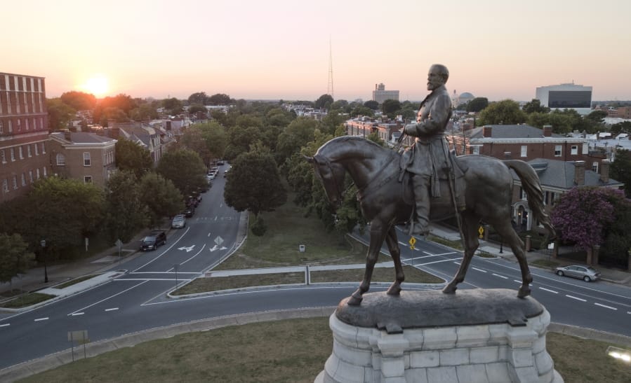 FILE - In this July 31, 2017, file photo, the sun sets behind the statue of Confederate Gen. Robert E. Lee on Monument Avenue in Richmond, Va. In a state where Confederate monuments have stood for more than a century and have recently become a flashpoint in the national debate over racial injustice, Virginians remain about evenly divided on whether the statues should stay or go, according to a new poll. The poll conducted this month by Hampton University and The Associated Press-NORC Center for Public Affairs Research found that 46% support removal of Confederate statues and 42% oppose removal.