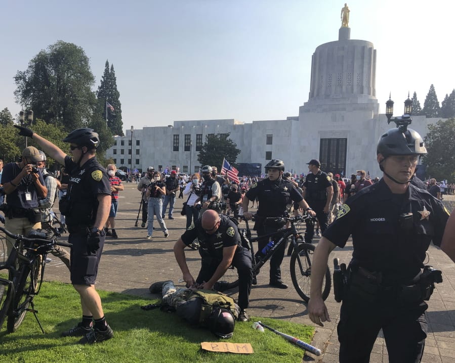 A protester is arrested during a protest at the Oregon State Capitol for a pro-Donald Trump rally at the Capitol in Salem, Ore. on Monday Sept. 7, 2020.
