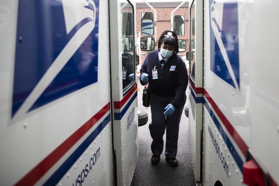 FILE - In this May 6, 2020, photo, United States Postal Service carrier Henrietta Dixon gets into her truck to deliver mail in Philadelphia.  Officials from six states and the District of Columbia are in court Thursday, Sept. 24,  to ask a federal judge to halt alleged slowdowns at the U.S.
