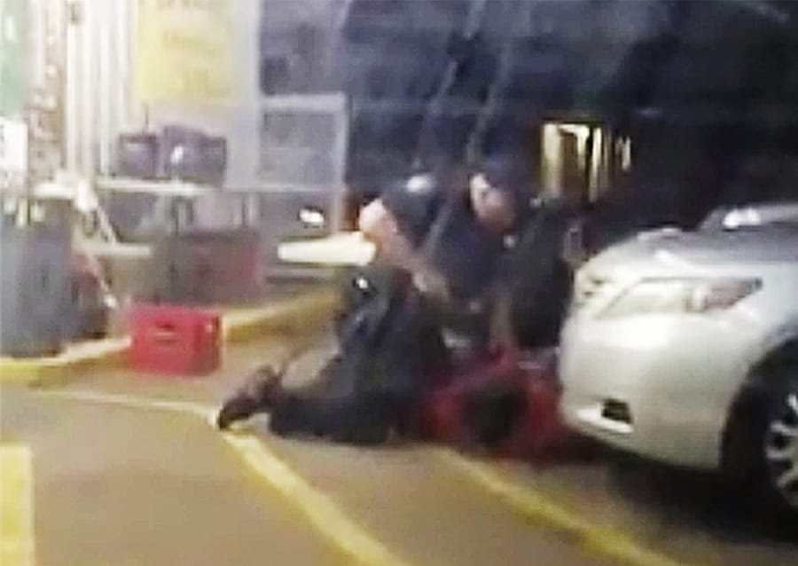 FILE - In this July 5, 2016, image made from video provided by Arthur Reed, Alton Sterling, in red, is restrained by two Baton Rouge police officers, one holding a gun, outside a convenience store in Baton Rouge, La. Moments later, one of the officers shot and killed Sterling, a black man who had been selling CDs outside the store, while he was on the ground. Howie Lake II, a white Louisiana police officer who assisted in the arrest in which Sterling was fatally shot, was dismissed Monday, Sept. 21, 2020, from a wrongful death lawsuit.