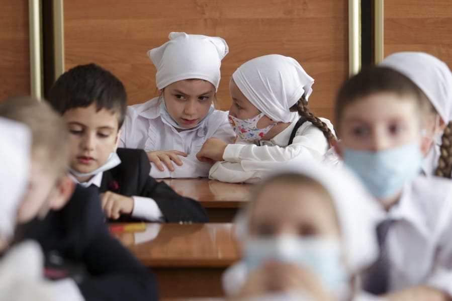 Pupils wearing face masks to protect against coronavirus sit in a classroom during a ceremony marking the start of classes at a school as part of the traditional opening of the school year known as &quot;Day of Knowledge&quot; in Grozny, Russia, Tuesday, Sept. 1, 2020. Across the country, schools start their usually festive opening day on Sept. 1.