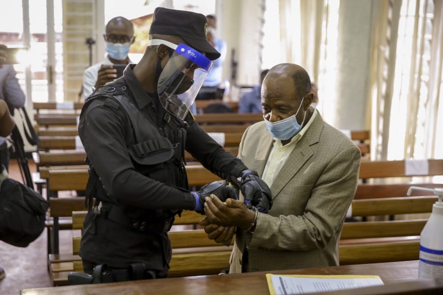 A policeman handcuffs Paul Rusesabagina, right, whose story inspired the film &quot;Hotel Rwanda&quot;, before leading him out of the Kicukiro Primary Court in the capital Kigali, Rwanda Monday, Sept. 14, 2020. A Rwandan court on Monday charged Paul Rusesabagina with terrorism, complicity in murder, and forming an armed rebel group, while Rusesabagina declined to respond to all 13 charges, saying some did not qualify as criminal offenses and saying that he denied the accusations when he was questioned by Rwandan investigators.