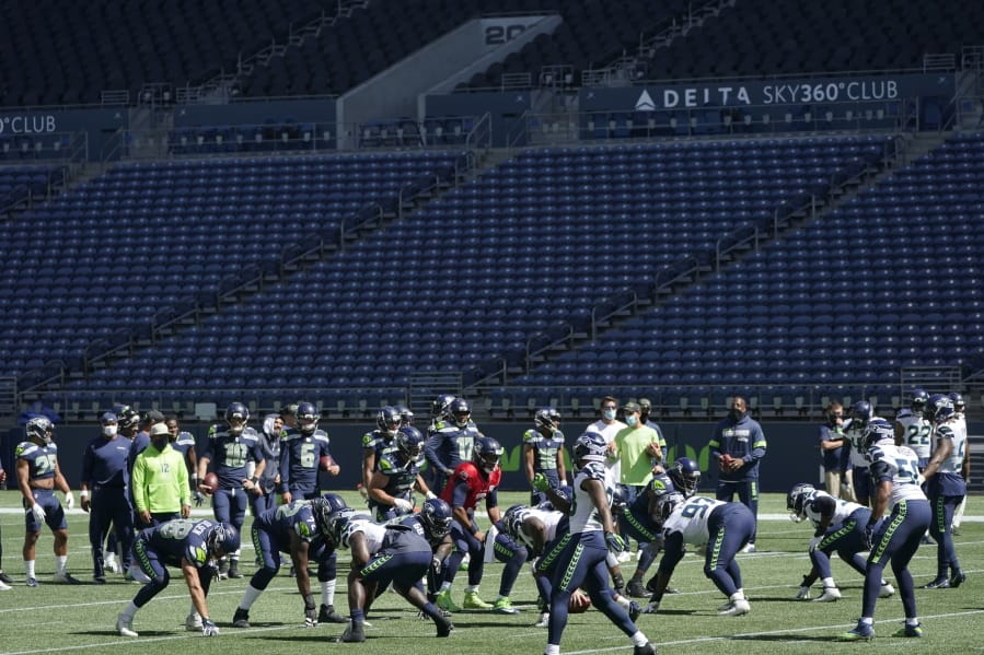 Seattle Seahawks quarterback Russell Wilson, center, waits for the snap during warmups in front of empty seats at CenturyLink Field before an NFL football mock game, Wednesday, Aug. 26, 2020, in Seattle. (AP Photo/Ted S.