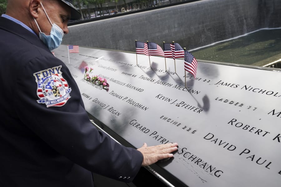 A mourner brushes water with his fingers over the name cut-outs of the deceased at the National September 11 Memorial and Museum, Friday, Sept. 11, 2020, in New York.