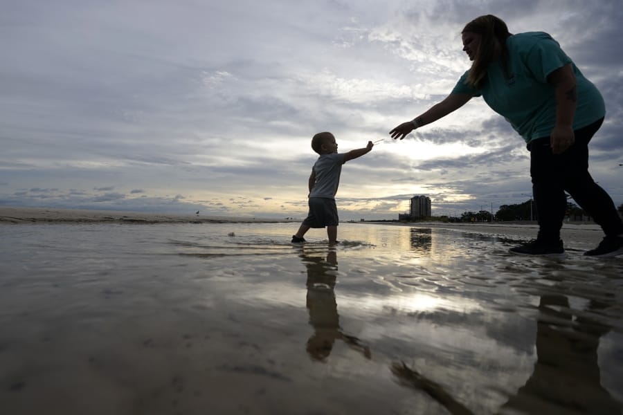 Nikita Pero of Gulfport, Miss., walks with her son Vinny Pero, 2, on the beach along the Gulf of Mexico in Biloxi, Miss., Monday, Sept. 14, 2020. Hurricane Sally is expected to make landfall along the Gulf Coast sometime through the night and morning.