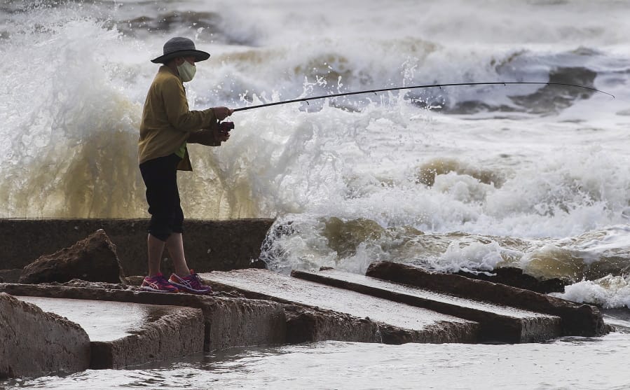 Waves crash as Houston resident Tinh Pham fishes from the rocks at Diamond Beach on the west end of the Galveston Seawall in Galveston, Texas on Saturday, Sept. 19, 2020. Tropical Storm Beta continues to move through the Gulf of Mexico and is expected to bring tidal surge and heavy rain to the area.