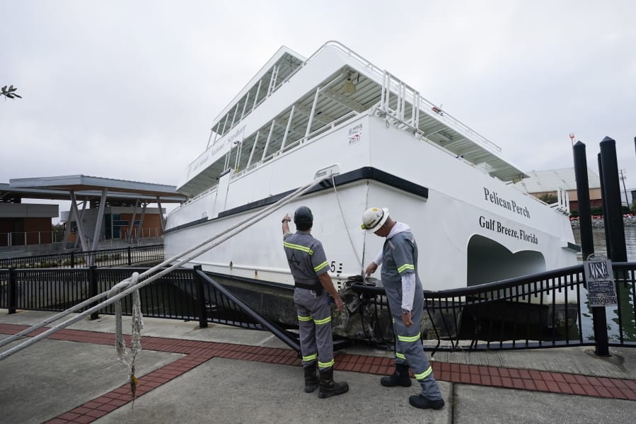 Workers look over a damaged ferry , Thursday, Sept. 17, 2020, in Pensacola, Fla.
