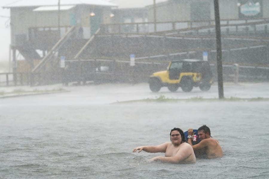 People play in a flooded parking lot at Navarre Beach, Tuesday, Sept. 15, 2020, in Pensacola Beach, Fla. Hurricane Sally is crawling toward the northern Gulf Coast at just 2 mph, a pace that&#039;s enabling the storm to gather huge amounts of water to eventually dump on land.