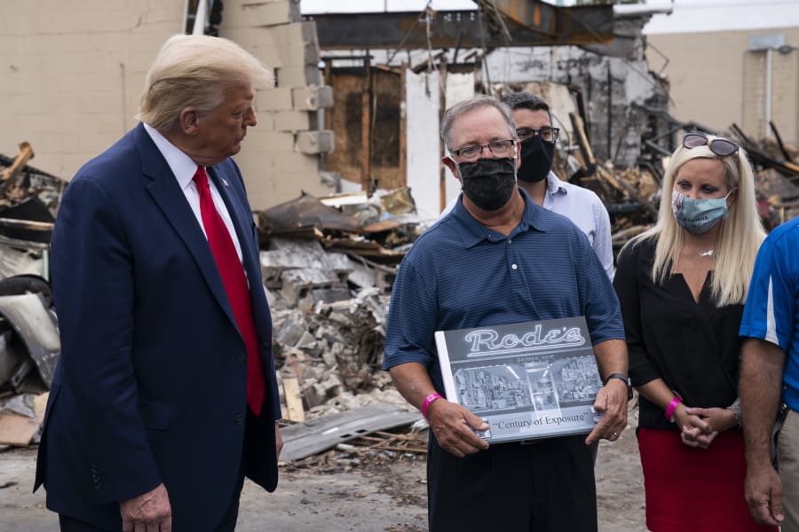 President Donald Trump talks with John Rode, the former owner of Rode&#039;s Camera Shop, as he speaks with business owners Tuesday, Sept. 1, 2020, during a tour of an area damaged during demonstrations after a police officer shot Jacob Blake in Kenosha, Wis.