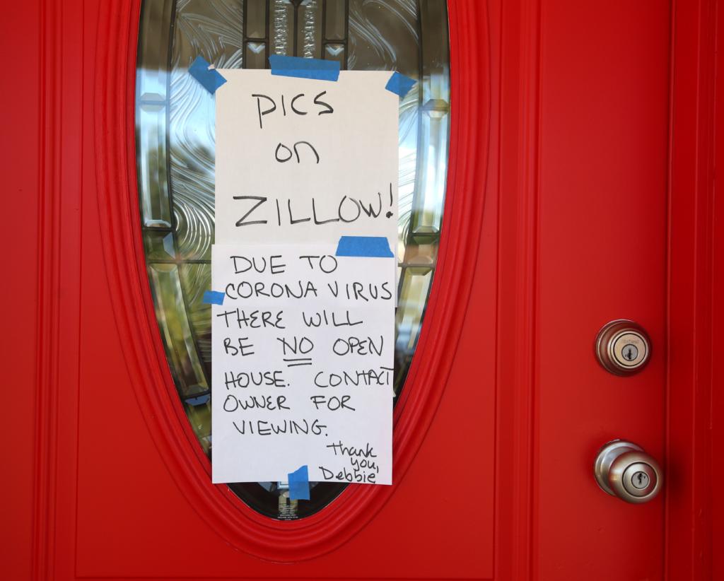 A sign on the front door of a home for sale in St. Petersburg, on March 23, 2020, that tells potential buyers that photos of the home are on Zillow.