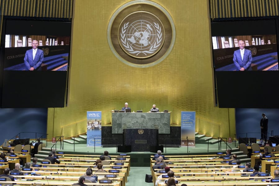 In this photo provided by the United Nations, President of the International Court of Justice, Judge Abdulqawi Ahmed Yusuf, is seen on screens as he addresses the United Nations General Assembly to commemorate the 75th anniversary of the United Nations.