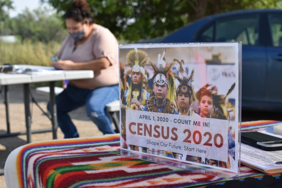 A sign promoting Native American participation in the U.S. census is displayed as Selena Rides Horse enters information into her phone on behalf of a member of the Crow Indian Tribe in Lodge Grass, Mont. on Wednesday, Aug. 26, 2020. There are more than 300 Native American reservations across the country, and almost all lag the rest of the country in participation in the census.