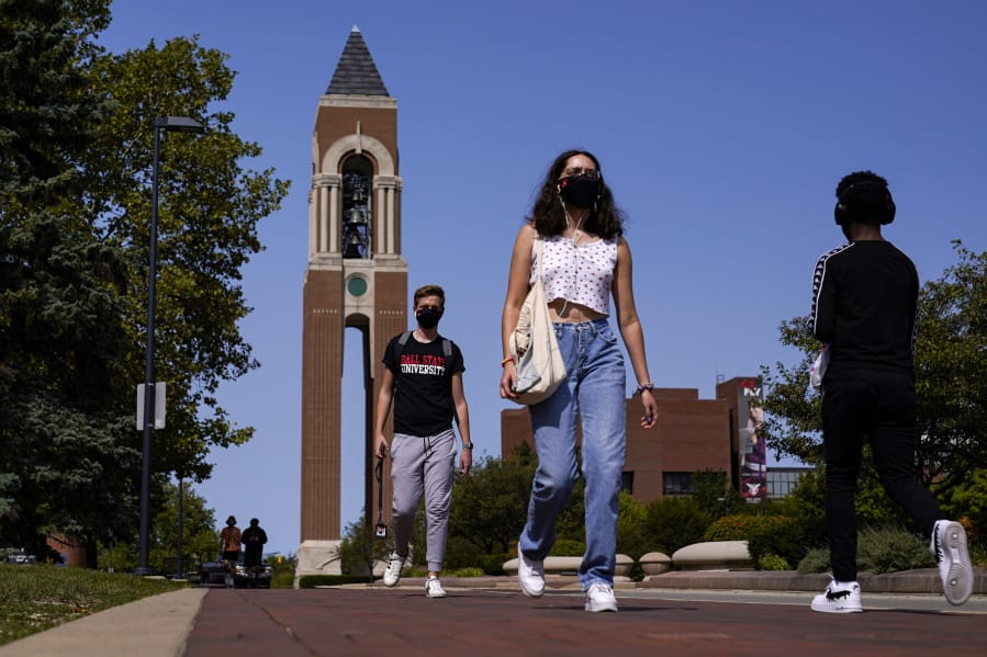 Masked students walk through the campus of Ball State University in Muncie, Ind., Thursday, Sept. 10, 2020. College towns across the U.S. have emerged as coronavirus hot spots in recent weeks as schools struggle to contain the virus. Out of nearly 600 students tested for the virus at Ball State, more than half have returned been found positive, according to data reported by the school. Dozens of infections have been blamed on off-campus parties, prompting university officials to admonish students.